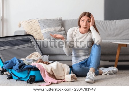Stressed young woman unpacking suitcase at home Royalty-Free Stock Photo #2304781949