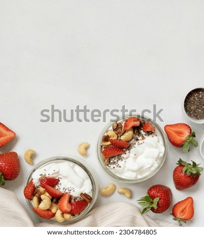 Greek yogurt, nuts and strawberries in a glass jars on a white table top view, copy space. Healthy breakfast with berries and nuts. Great way to eat protein