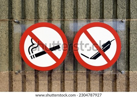 No smoking and no cell phone notices in a building. Smoking prohibited