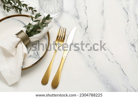 Plate with folded napkin and gold cutlery on grunge white background Royalty-Free Stock Photo #2304788225
