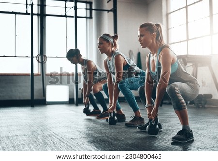 Kettlebell, fitness and women in a gym, training or workout goal with wellness, class or exercise. Female athlete, girls or squat with equipment, sports or relax with healthy lifestyle or challenge Royalty-Free Stock Photo #2304800465