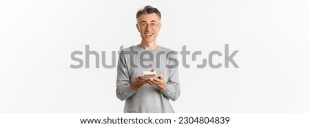 Image of handsome middle-aged man looking surprised and happy, being congratulated with birthday, holding b-day cake and smiling amazed, celebrating over white background.