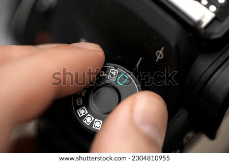 Fingers selecting automatic mode on a professional camera. man putting the automatic mode on the camera. Dial with automatic mode in digital photography cameras. Man selecting auto mode