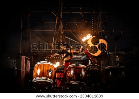 Japanese warrior handling performance among traditional Japanese drums called Taiko. An artist performing on stage with fire in his hands. Samurai tradition. Japan Royalty-Free Stock Photo #2304811839