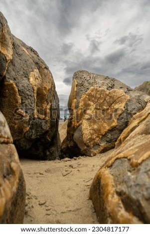 Looking at someone through the crack in a colourful boulder in Moeraki New Zealand