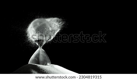 Hourglass add more sand of time on white sand over black background. White hourglass show more time Deadline extended time management hope concept hour glass, life clock passing by Royalty-Free Stock Photo #2304819315