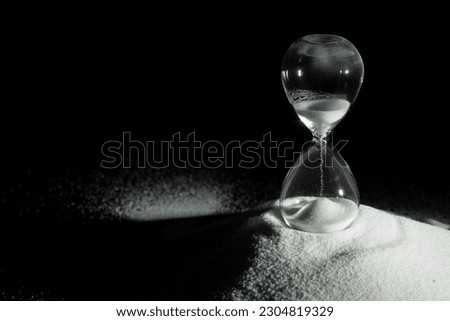 Hourglass add more sand of time on white sand over black background. White hourglass show more time Deadline extended time management hope concept hour glass, life clock passing by