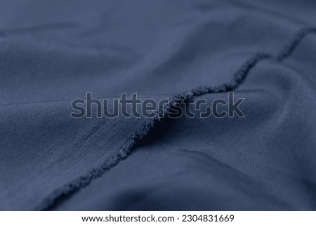 Folded indigo blue colored fabric texture background. This fabric is made of polyester and spandex. Royalty-Free Stock Photo #2304831669
