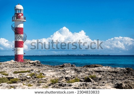 Photograph of the lighthouse at the tip of the lighthouse in the hotel zone of Cancun in Mexico. It is a paradisiacal cliff overlooking the turquoise caribbean sea under the tropical mexican sun.