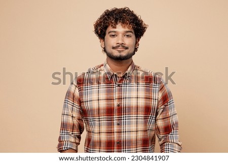Confident satisfied cool student Indian man wearing checkered brown shirt casual clothes looking camera isolated on plain pastel light beige color background studio portrait. People lifestyle concept Royalty-Free Stock Photo #2304841907