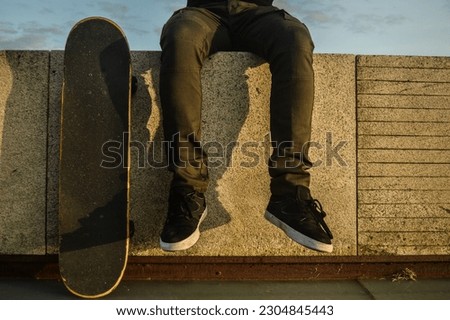 man sitting with a skateboard at sunset