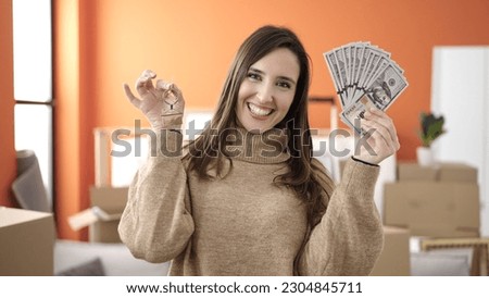 Beautiful hispanic woman smiling confident holding money and keys at new home