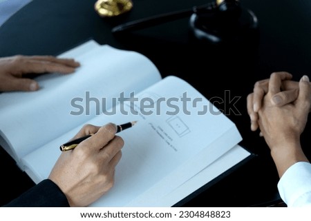 lawyer signing documents with female assistant handing over documents on desk in law firm office