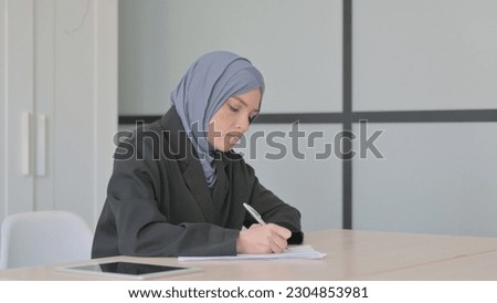 Muslim Businesswoman Writing Letter at Work, Paperwork