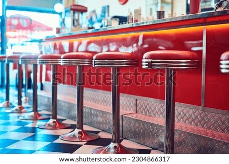 Trendy, vintage and retro interior in a diner, restaurant or cafeteria with funky decor. Booth, old school and chairs by a counter or bar in a groovy, vibrant and stylish old fashioned empty cafe. Royalty-Free Stock Photo #2304866317