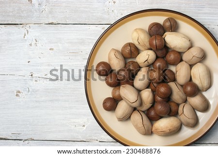 Pecan and macadamia in the ceramic plate on the white wooden table
