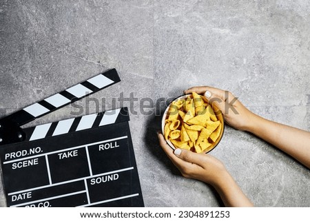 clapper board of video cinema in studio and hands holding a bowl of cone corn chips in glass bowl 