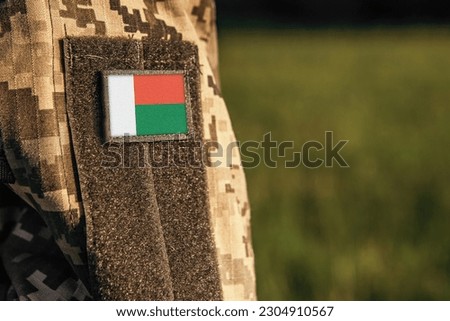 Close up millitary woman or man shoulder arm sleeve with Madagascar flag patch. Troops army, soldier camouflage uniform. Armed Forces, empty copy space for text

