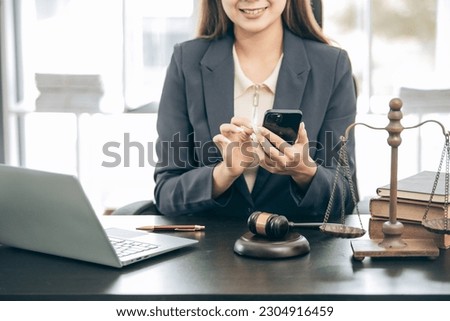 Beautiful young woman lawyer sitting in front of laptop in room with documents and smartphone with empty hammer and scale next to it justice and legal concept