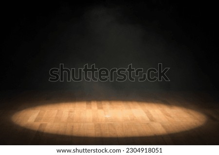 Single focus of light on a theater stage without anything, focus of light on a wooden floor and black background, closed beam of light on stage.