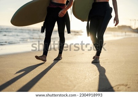 Cropped picture of surfers walking on a beach and going surfing.