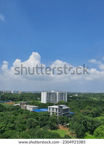 Some buildings in the middle of a forest under the blue Sky. 