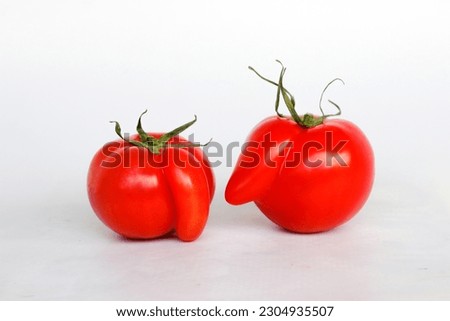 Deformed red tomatoes on a white background ,Funny deformed red tomato with a nose  Royalty-Free Stock Photo #2304935507
