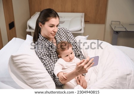 Mother and ill child watching video on smartphone in hospital room