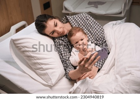 Female showing cartoon to her ill baby in ward