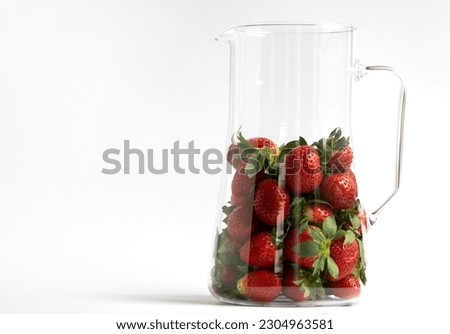 Red strawberries on a white background with copy space for your text. Ripe berry in a glass jar with highlights