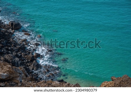 Aerial view of sea waves and fantastic Rocky coast, Beautiful clear underwater surface. Sea rocky bottom under transparent blue water. Clear turquoise sea surface rippled with sun ray reflection.