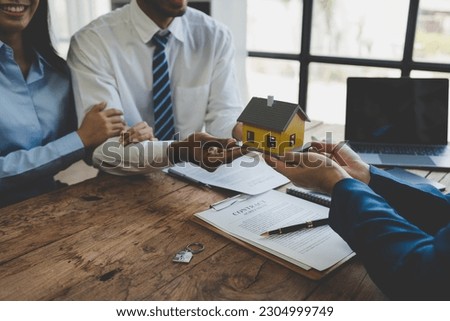 Real estate agent or sales manager is handing over a mockup house after offering terms and signing a home purchase contract and free home insurance, finance and after sales service concept.