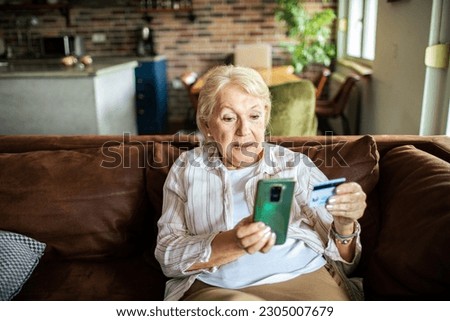 Close up of a Senior woman using a credit card to make an online purchase on a smart phone