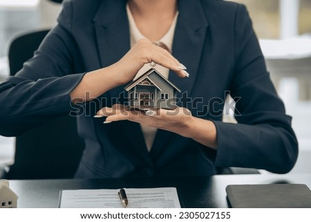 Young beautiful Asian real estate agent uses a small calculator and house models to present and advise clients on buying and selling home designs. real estate business ideas