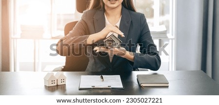 Young beautiful Asian real estate agent uses a small calculator and house models to present and advise clients on buying and selling home designs. real estate business ideas