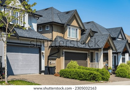 A perfect neighborhood. Houses in suburb at Spring in the north America. Real Estate Exterior Front Houses on sunny day. Big custom houses with nicely landscaped front yard-British Columbia Canada Royalty-Free Stock Photo #2305032163