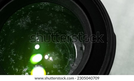 Close up image of moldy camera lens with colored light reflection on the lens and visible fungus sticking on the lens.