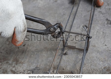 Workers hands using steel wire and pincers to secure rebar before concrete is poured over it Royalty-Free Stock Photo #2305043857
