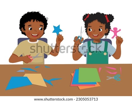 Cute little African kids boy and girl cutting colored paper with scissors making paper cut art craft