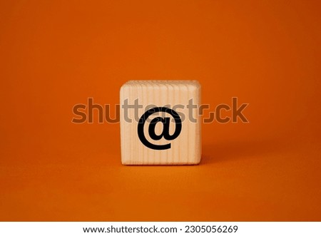 At symbol. At sign on wooden blocks. Beautiful orange background. Business and at sign concept. Copy space