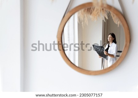 A woman doctor in a white coat takes an X-ray picture of a patient. Concept mirror, abstraction, doctor, treatment, beige tones