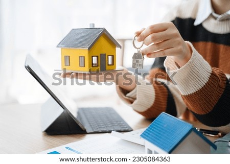 Asian woman gives the house keys to the client after signing a real  contract and tenant, home insurance.