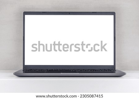 white mock-up on a laptop screen on a white table against a gray wall close-up front view