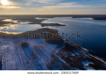 Beautiful winter landscape - drone aerial photo sunset time - frozen Wigry lake, forest and sun reflections in water and ice