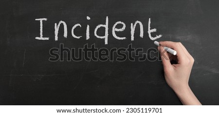 A woman's hand write text incident with chalk on chalkboard Royalty-Free Stock Photo #2305119701