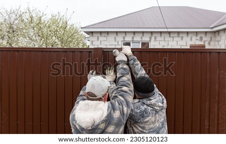 Workers install a metal profile fence.