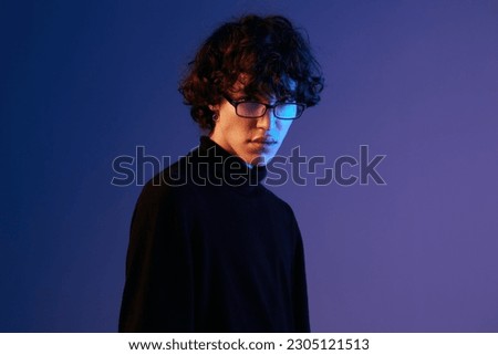 Male fashion in black model poses in glasses, hipster lifestyle, portrait blue background, mixed neon light, fashion style and trends boys teenager, copy space