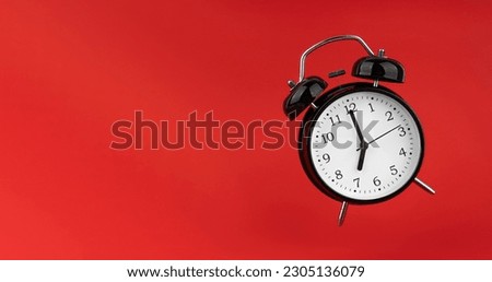 Black alarm clock on a red background.