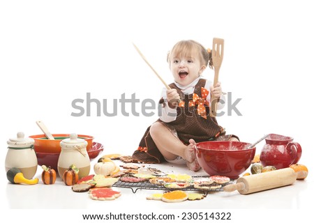 Thanksgiving baking.  Adorable toddler surrounded by bowls and utensils and Thanksgiving cookies.  Isolated on white with room for your text.