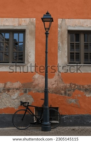 Vertical street photo of a building with a street lamp and a bicycle nearby